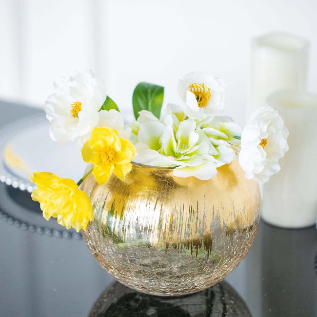 Gold vase with white and yellow flowers arranged elegantly.