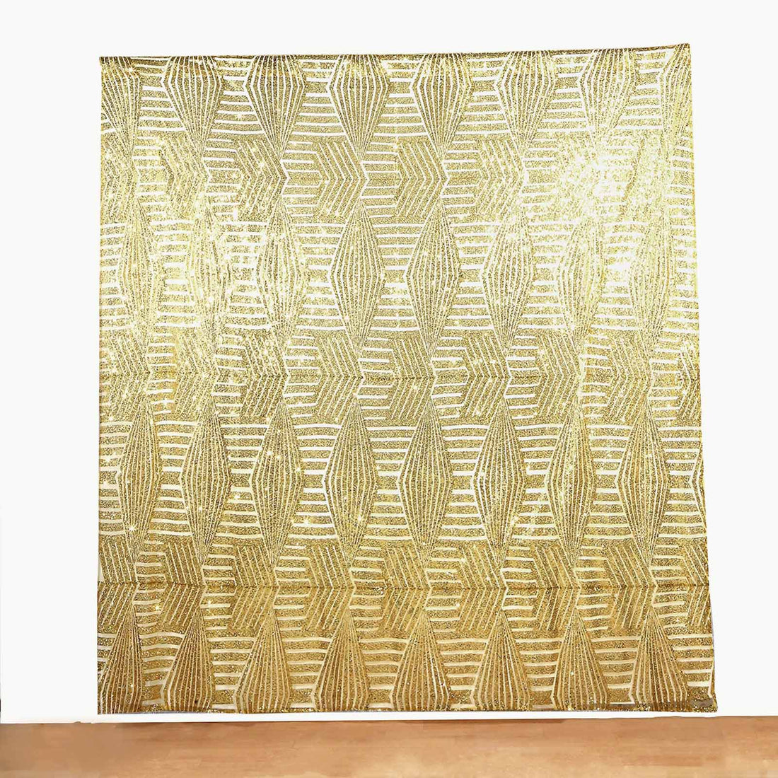Gold patterned fabric backdrop with geometric design.