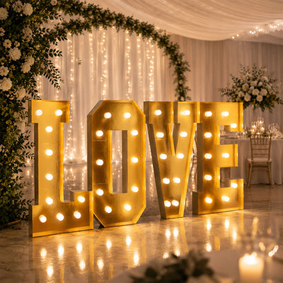 Gold illuminated LOVE letters at a romantic wedding reception backdrop