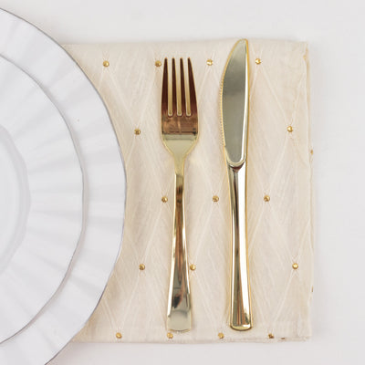 Gold knife and fork on elegant cream quilted placemat beside white plates