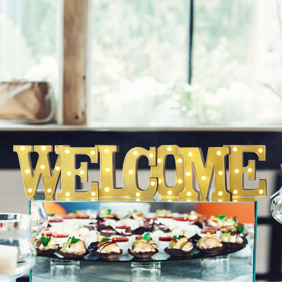 "Bright welcome sign displayed at an event with cupcakes in the background."