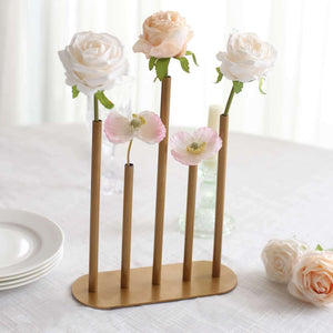 Gold vase with pastel flowers on a table setting.