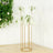Gold flower stand with white wisteria blooms and green leaves.