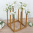 Gold flower vase holder with white roses on a wooden table.
