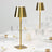 Gold table lamp with a modern design on a dining table setting.