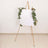 Blank easel with greenery accents on a plain background