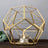 Gold geometric candle holder with a glass insert.