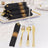 Elegant black napkins with gold stripes, set with gold cutlery and glassware.