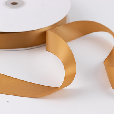Gold satin ribbon roll on white background close-up