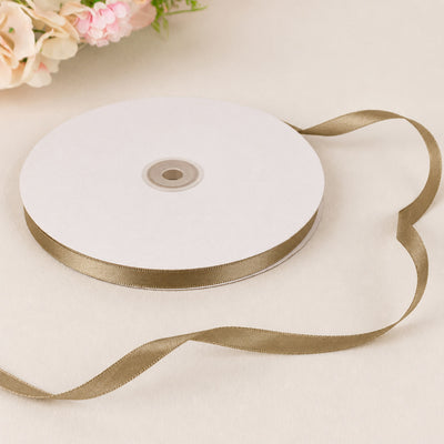 Gold satin ribbon roll on white spool with floral background