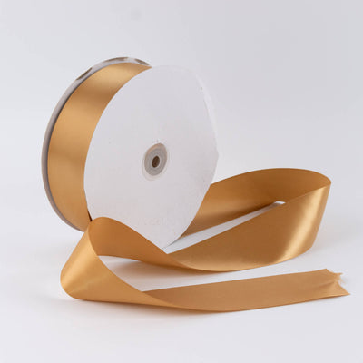 Gold satin ribbon spool on white background