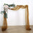 Elegant wedding arch adorned with floral accents and flowing fabric drapes.
