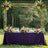 Outdoor wedding reception table adorned with flowers and a purple tablecloth.
