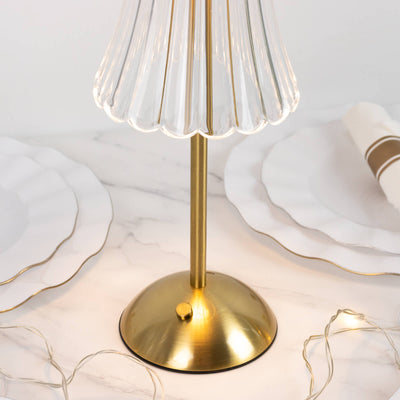 Gold table lamp with clear ribbed glass shade on marble surface