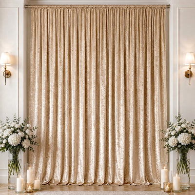 Gold velvet curtain backdrop with floral arrangements and candles indoors