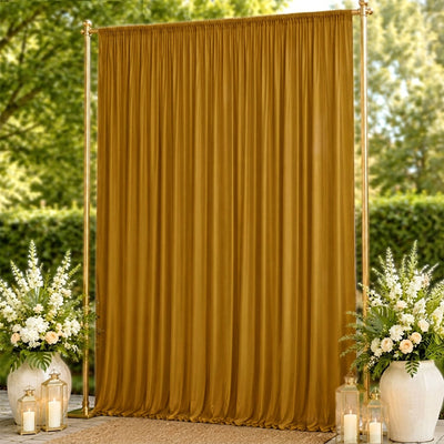 Gold wedding backdrop with sheer curtain, floral arrangements, and lanterns outdoors
