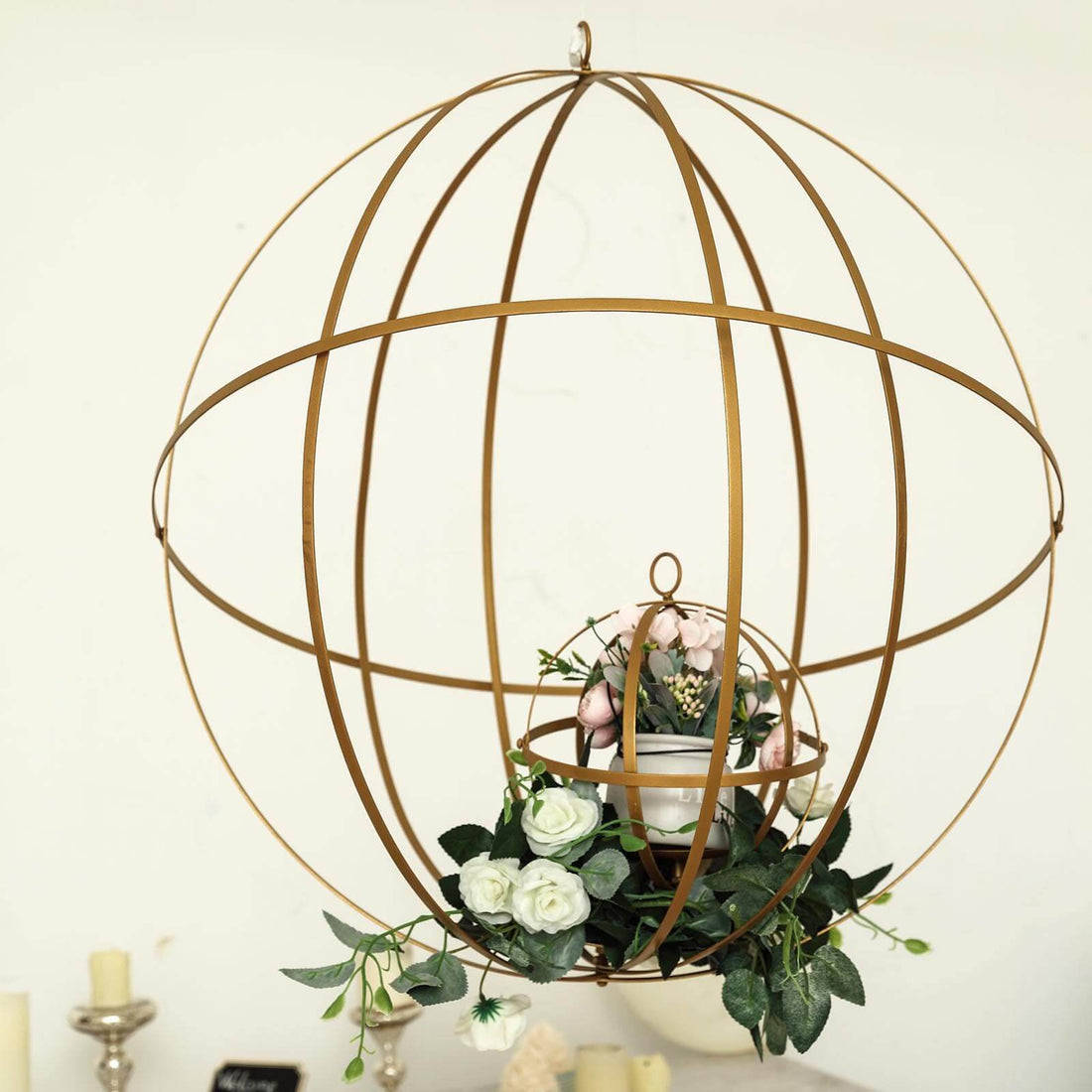 Gold metal globe planter with flowers and greenery.