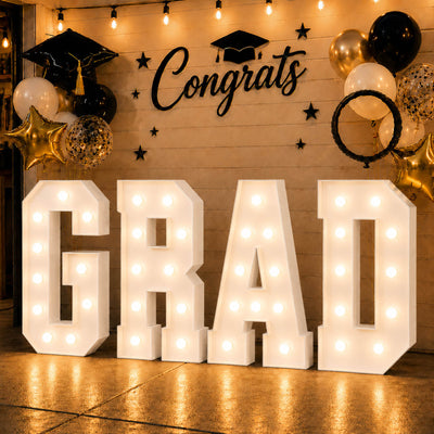 Graduation party backdrop with lights, balloons, and “Congrats Grad” sign