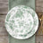 Green floral dinnerware set on rustic wooden table with gold flatware