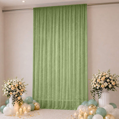 Green sheer backdrop with floral arrangements, balloons, and candles for a party setup