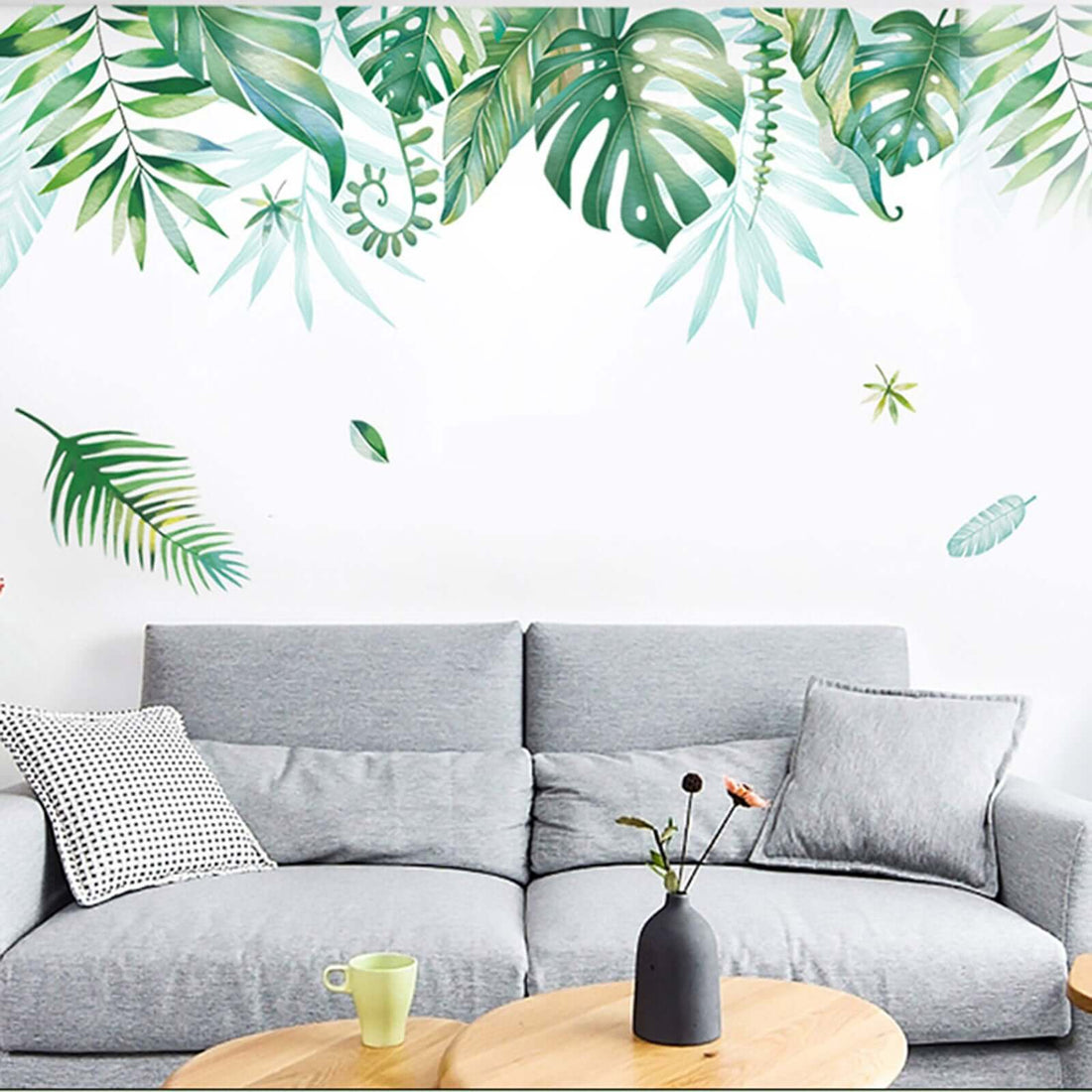 Modern living room with green plant wall art, gray sofa, and wooden coffee table.