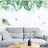 Modern living room with green plant wall art, gray sofa, and wooden coffee table.