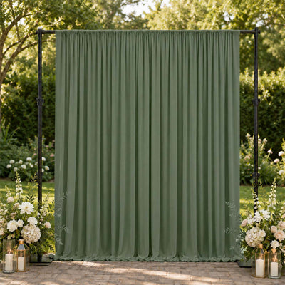 Green wedding backdrop curtain with floral arrangements and lanterns outdoors