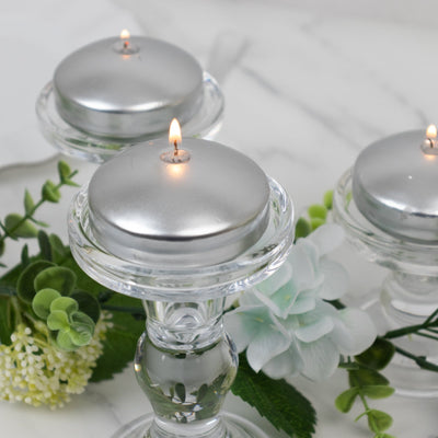 Silver tealight candles on crystal holders with floral accents.