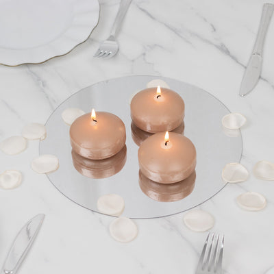 Three round candles on a mirrored surface with rose petals.