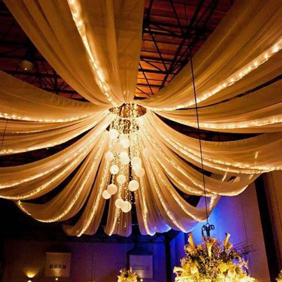 Elegant ceiling drapery with lights and chandelier for event decoration.
