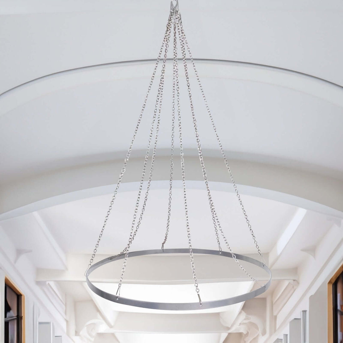 Modern circular chandelier with sleek metallic design hanging in a bright space.