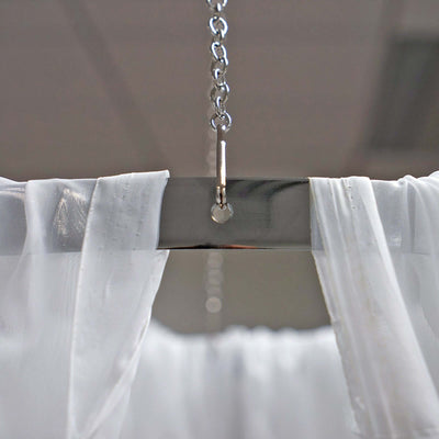 Curtain hanging from a polished metal rod with chain attachment.