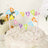 Colorful "Happy Birthday" cake topper with striped straws on a decorated cake.