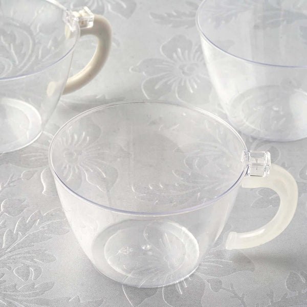 Clear plastic cups with handles on a textured surface.