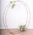 Gold circular flower arch with floral arrangement on a plain background.