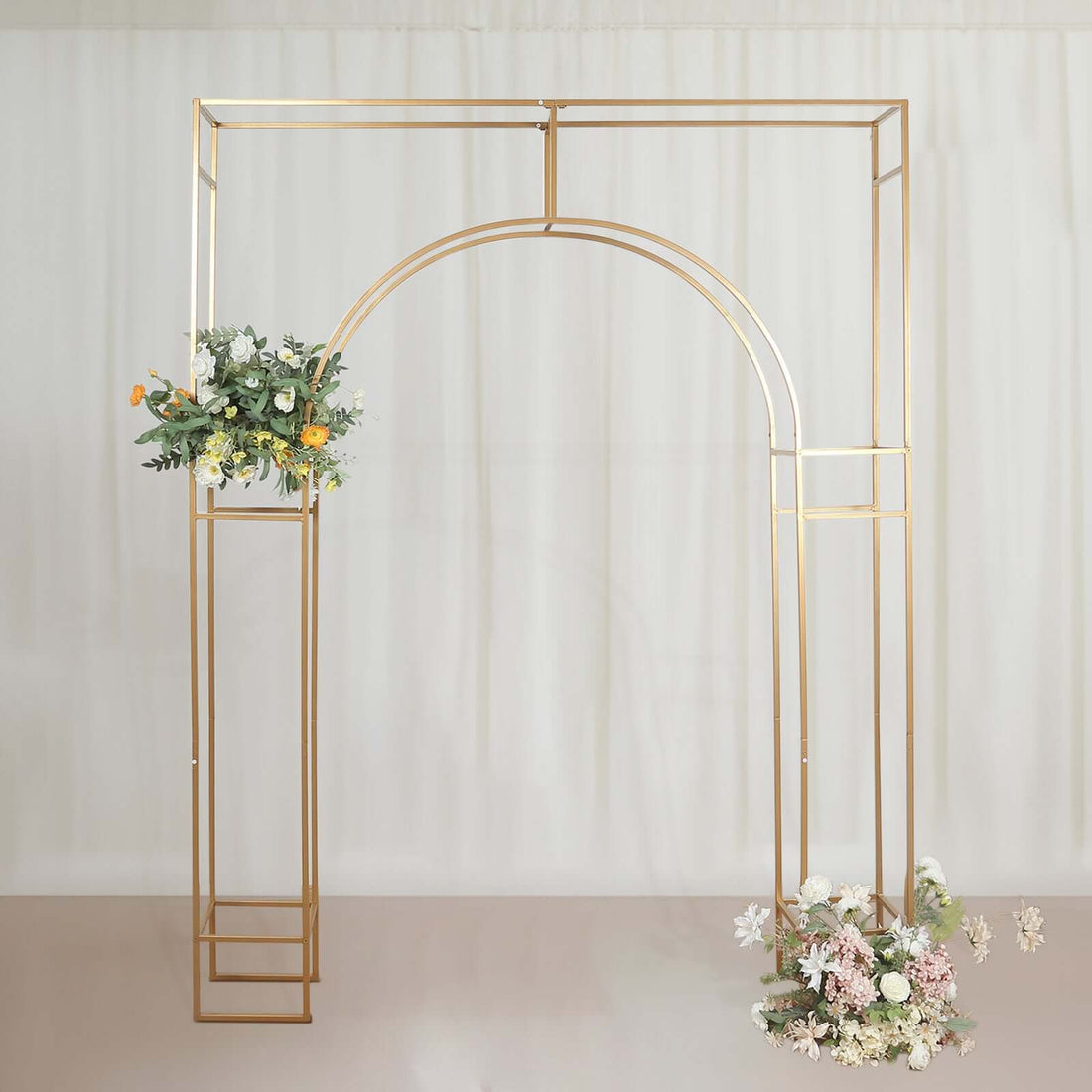 Gold wedding arch with floral arrangements on a soft backdrop.