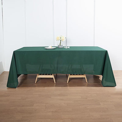 Green tablecloth draped over a table with decorative flowers and a plate.