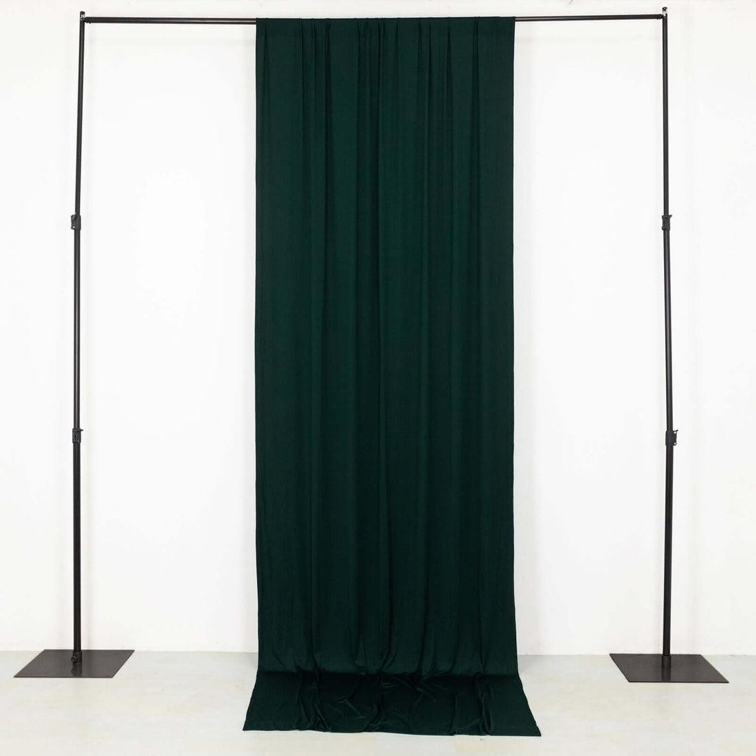 Dark green fabric draped on a black stand in a studio setting