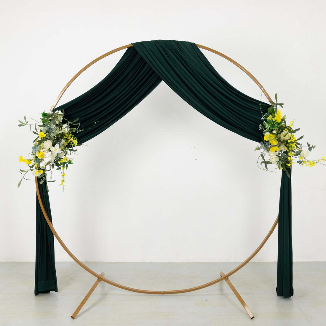 Gold metal arch with green drapery and floral arrangements