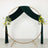 Gold metal arch with green drapery and floral arrangements