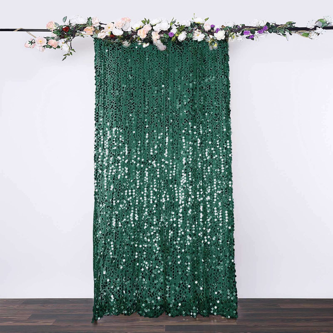 Green sequin backdrop draped with floral accents for events and photography.