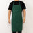 Green apron worn by a person, featuring pockets and adjustable neck strap.