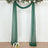 Green sheer fabric drapes with floral arrangement for event decoration.