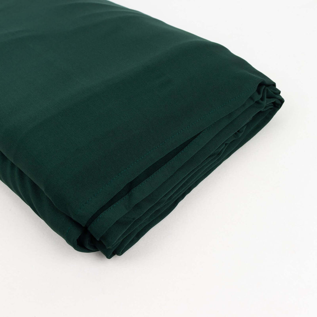 Dark green folded fabric on a plain background