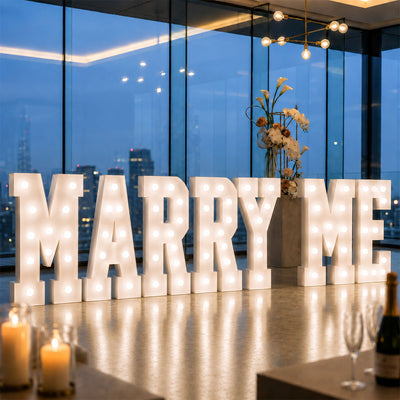 Illuminated Marry Me marquee at elegant wedding reception venue by city windows