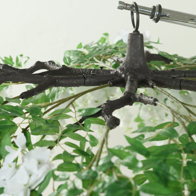 Decorative chandelier with branch-like design and green foliage.