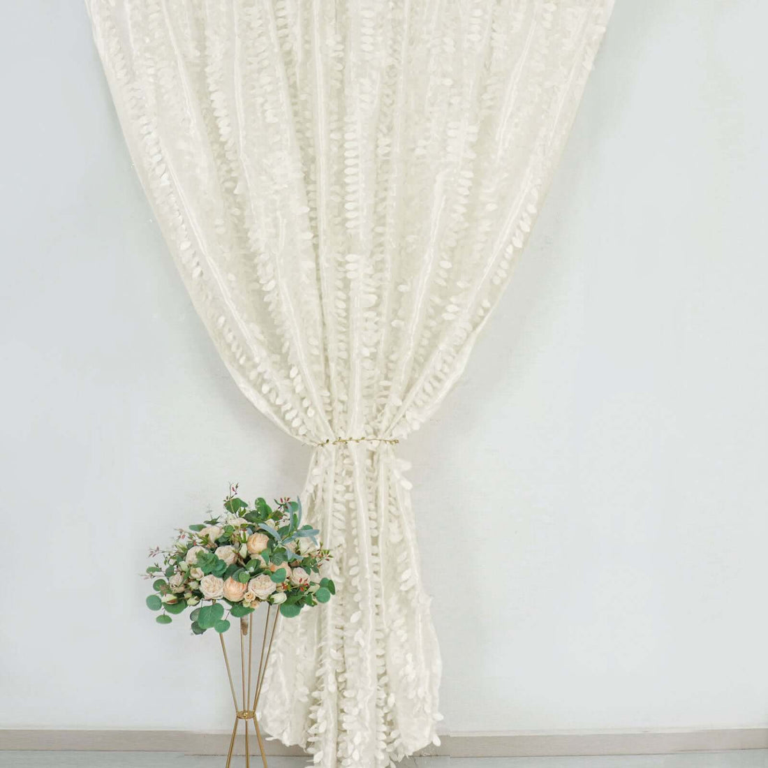 Elegant white curtain draped with floral arrangement in a modern setting.