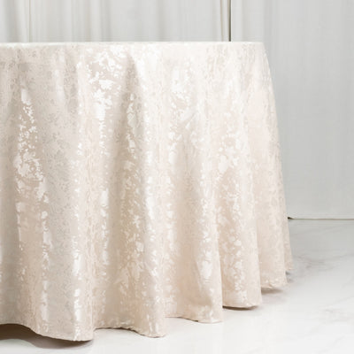 Ivory jacquard tablecloth draped over a round table in a bright room