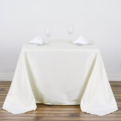 Elegant ivory tablecloth draped over a table set for two with glasses and napkins.