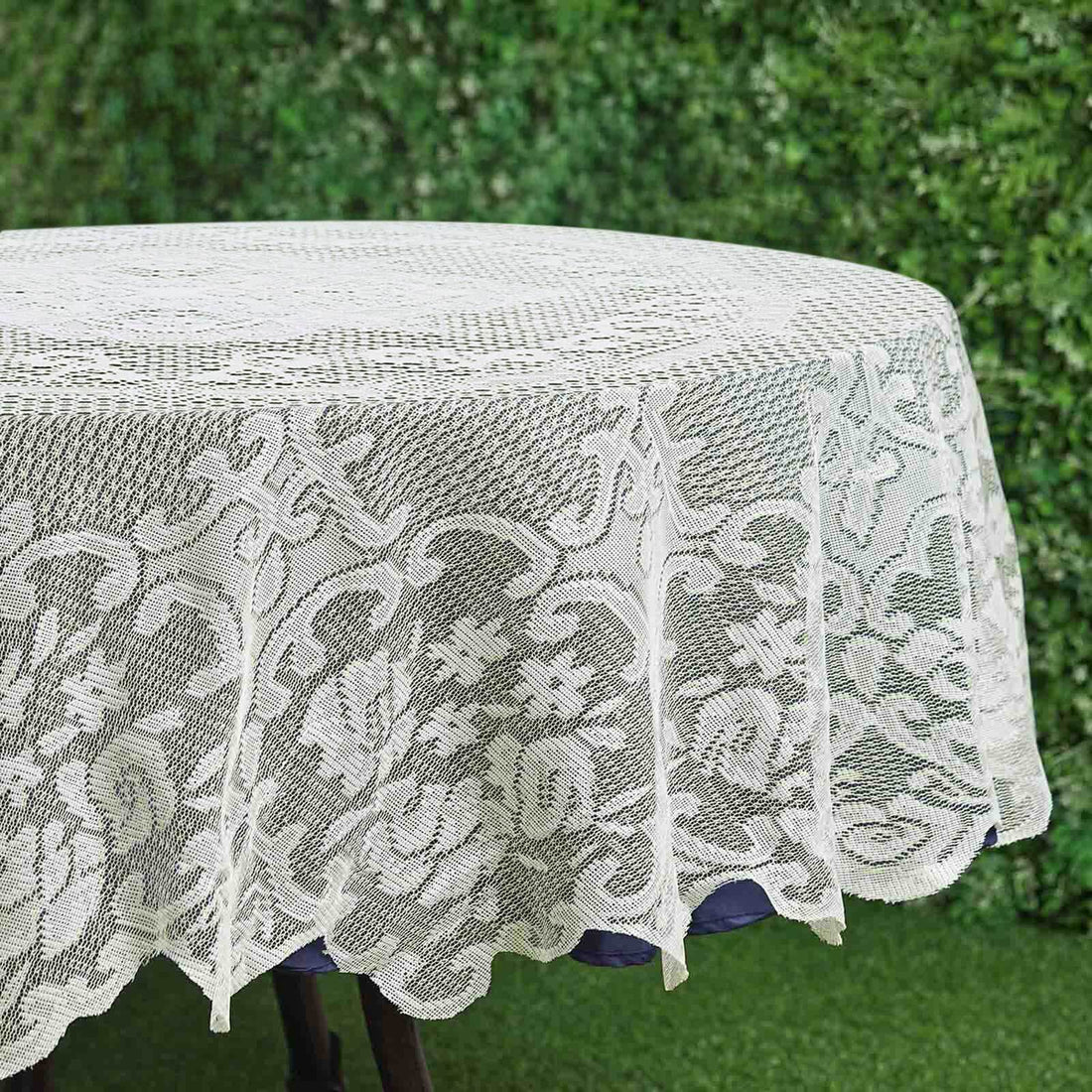White lace tablecloth with floral design on round table.